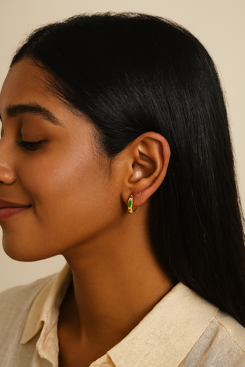 Close-up of a woman wearing a green and gold earring against a neutral background