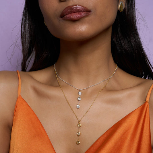 Woman wearing an orange dress with a necklace against a purple background