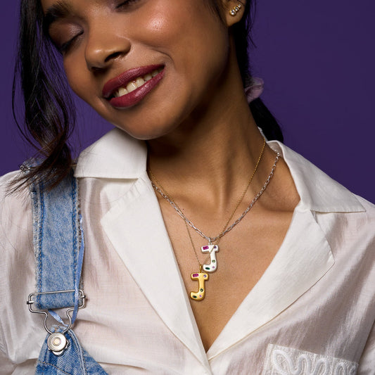 Woman wearing a white blouse and blue denim overalls with a purple background