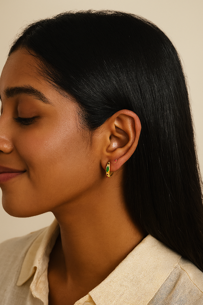 Close-up of a woman wearing a green and gold earring against a neutral background