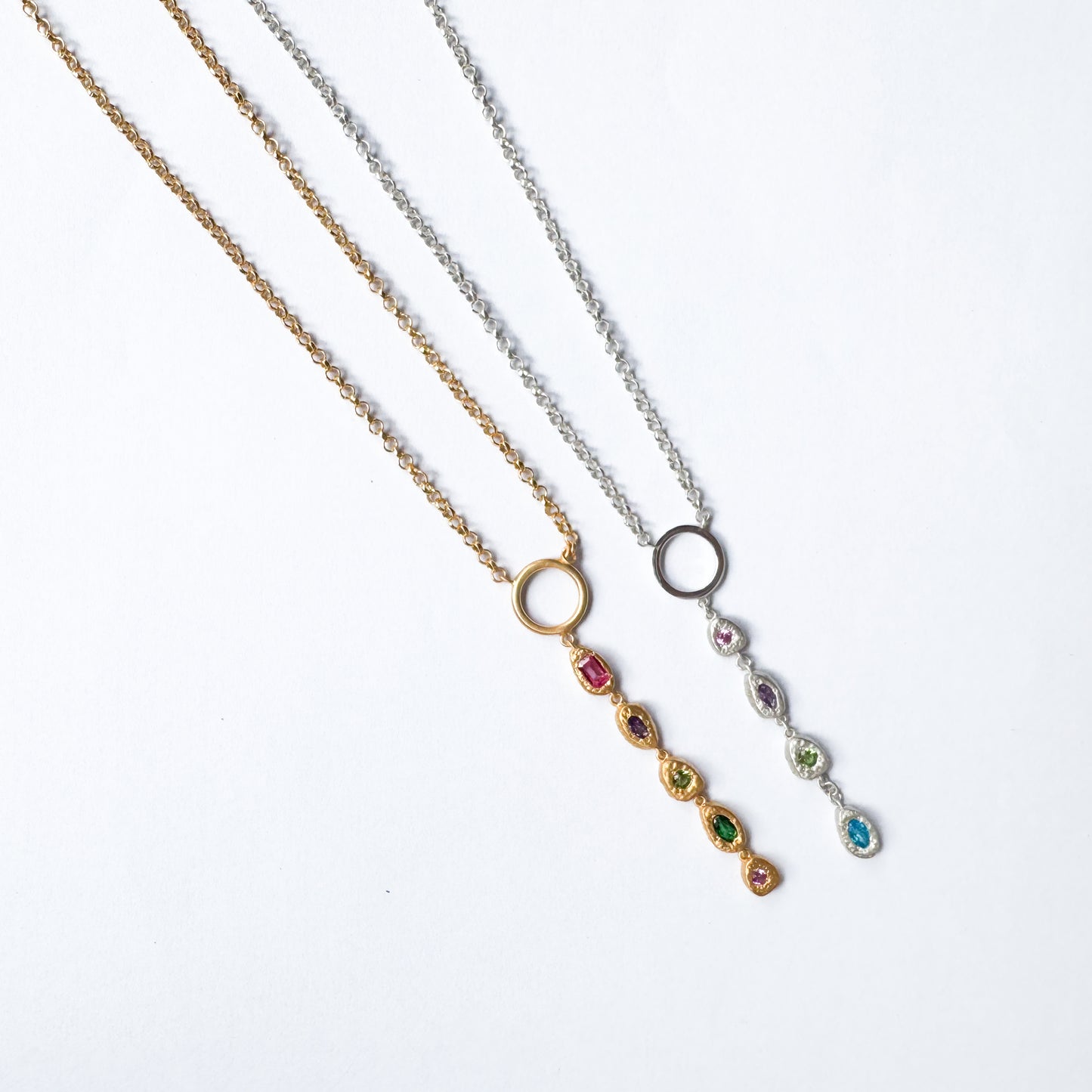 Three necklaces with gemstone pendants on a white background