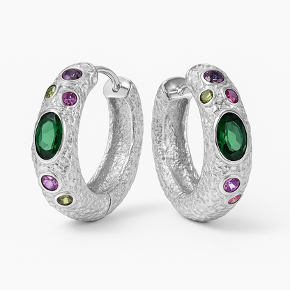 Silver hoop earrings with green and purple gemstones on a white background